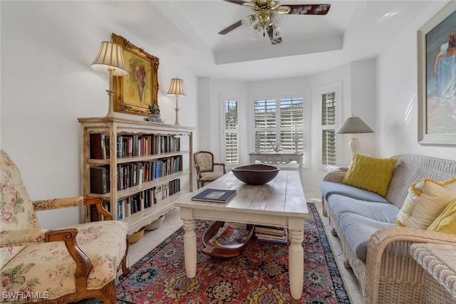 living area featuring a ceiling fan and a raised ceiling
