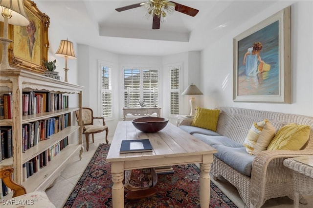 living area featuring a tray ceiling and ceiling fan