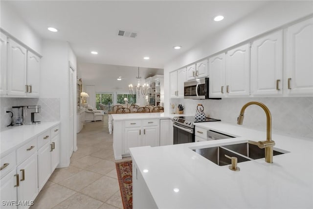 kitchen featuring backsplash, visible vents, a sink, a peninsula, and appliances with stainless steel finishes