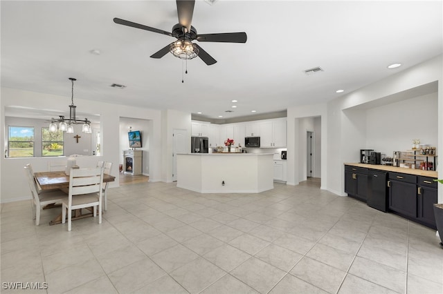 kitchen featuring hanging light fixtures, light tile patterned flooring, white cabinets, ceiling fan with notable chandelier, and stainless steel refrigerator