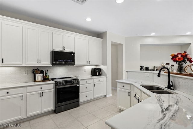 kitchen featuring black range oven, backsplash, sink, light tile patterned flooring, and white cabinets