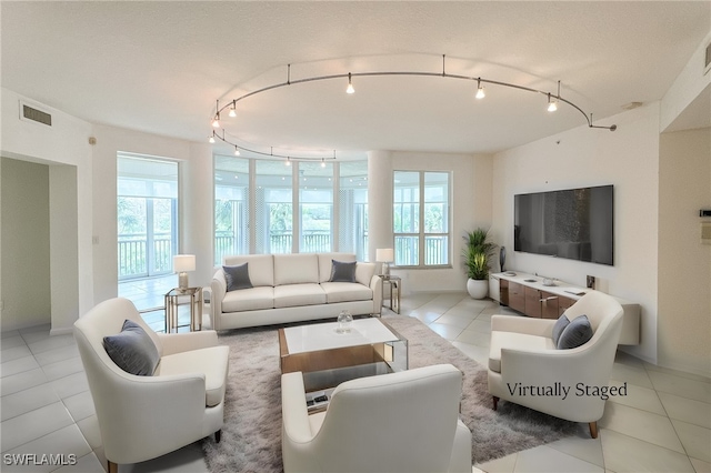 living room featuring a textured ceiling, plenty of natural light, and light tile patterned floors