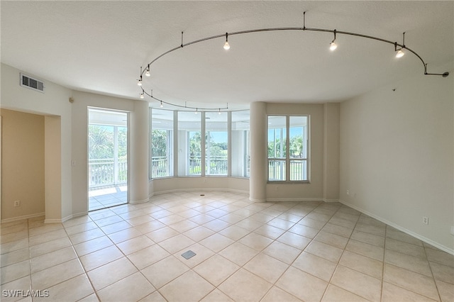 tiled empty room featuring track lighting, plenty of natural light, and a textured ceiling