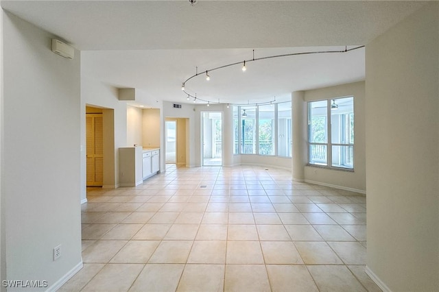 unfurnished room with rail lighting, baseboards, and light tile patterned flooring