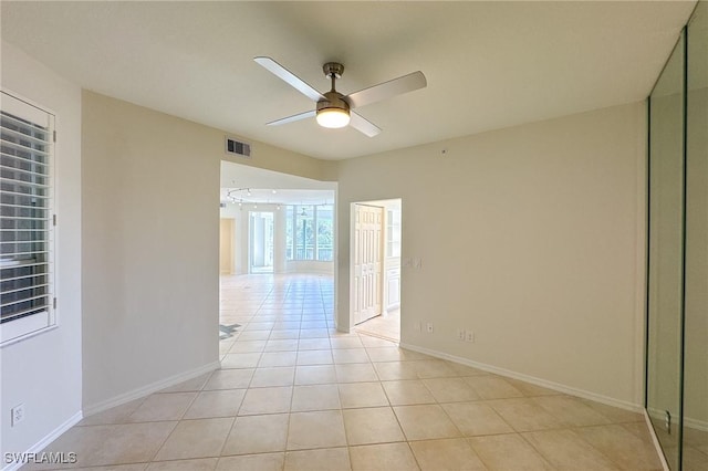 empty room featuring visible vents, ceiling fan, baseboards, and light tile patterned floors