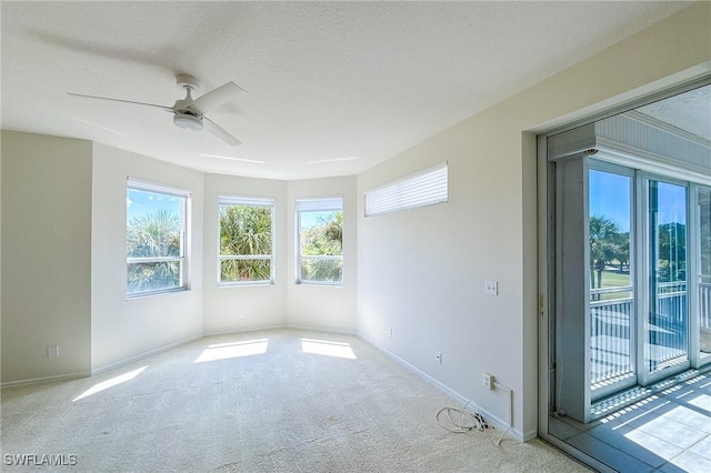 carpeted empty room featuring a textured ceiling, a ceiling fan, and baseboards