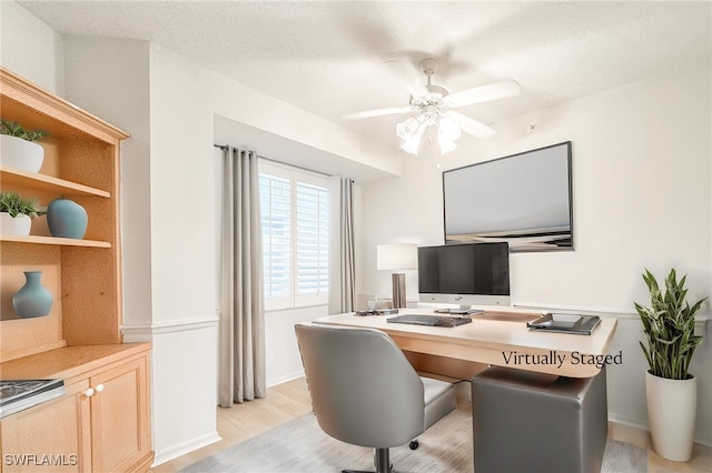 home office with a textured ceiling, light hardwood / wood-style floors, ceiling fan, and built in desk