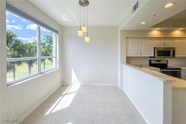 kitchen with pendant lighting, kitchen peninsula, light tile patterned floors, and stainless steel appliances