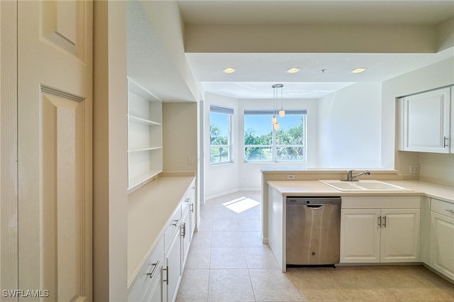 kitchen with light tile patterned flooring, pendant lighting, sink, white cabinets, and stainless steel dishwasher