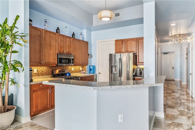 kitchen with sink, an island with sink, stainless steel appliances, decorative light fixtures, and decorative backsplash