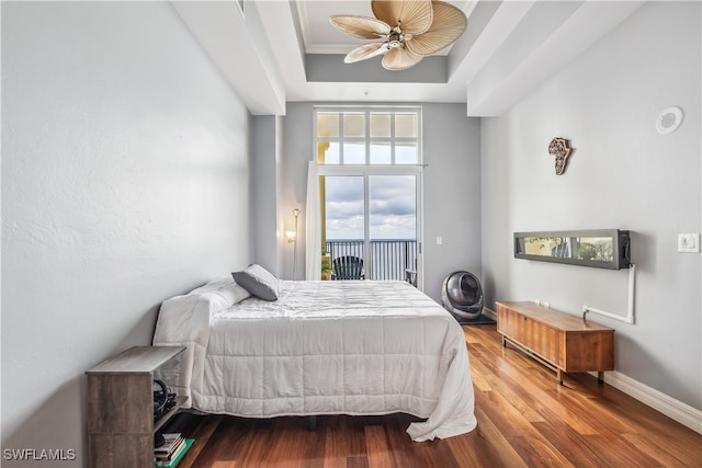 bedroom with access to exterior, hardwood / wood-style flooring, a tray ceiling, ornamental molding, and ceiling fan