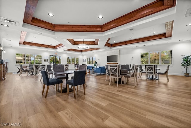 dining space with beamed ceiling, coffered ceiling, a tray ceiling, and light hardwood / wood-style floors