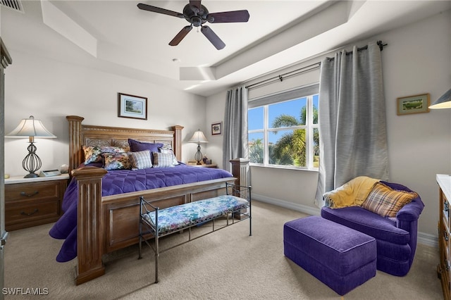 carpeted bedroom featuring ceiling fan and a tray ceiling