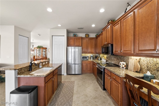 kitchen with a kitchen island with sink, stainless steel appliances, sink, light stone counters, and tasteful backsplash