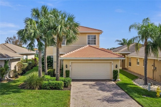 mediterranean / spanish house featuring a front yard, an attached garage, stucco siding, a tiled roof, and decorative driveway