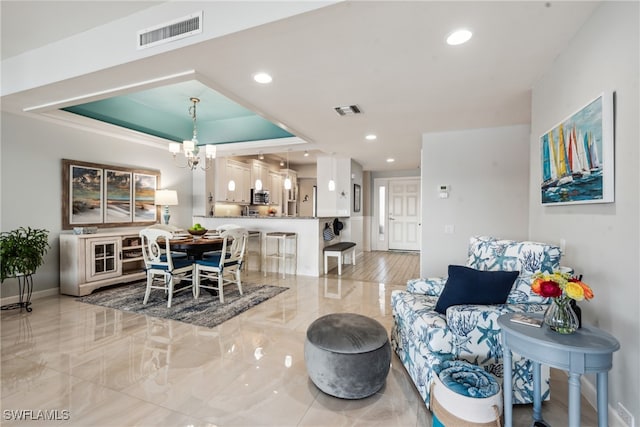 living room featuring a raised ceiling and a chandelier