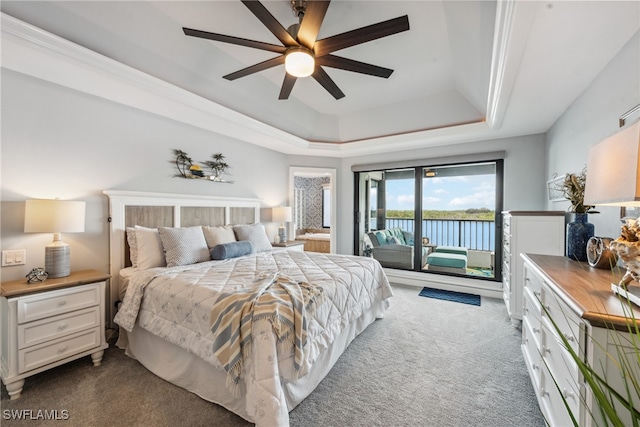 bedroom featuring ceiling fan, dark carpet, access to outside, and a tray ceiling