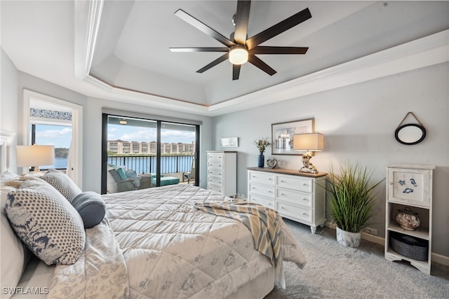 carpeted bedroom with access to outside, a water view, ceiling fan, a tray ceiling, and multiple windows