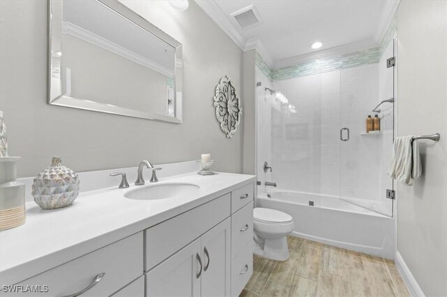 full bathroom with tiled shower / bath combo, crown molding, wood-type flooring, toilet, and vanity