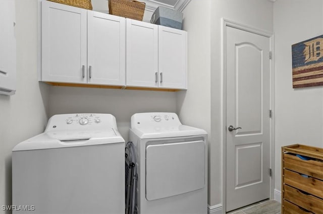 laundry area featuring washer and dryer, light wood-type flooring, crown molding, and cabinets