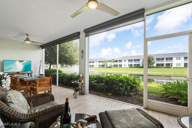 sunroom featuring ceiling fan and a water view