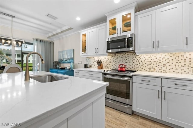 kitchen featuring appliances with stainless steel finishes, backsplash, ornamental molding, sink, and white cabinets