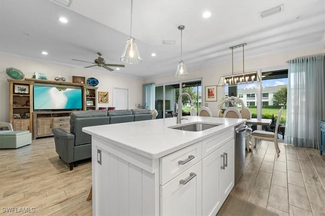 kitchen with a center island with sink, white cabinets, sink, ceiling fan, and decorative light fixtures