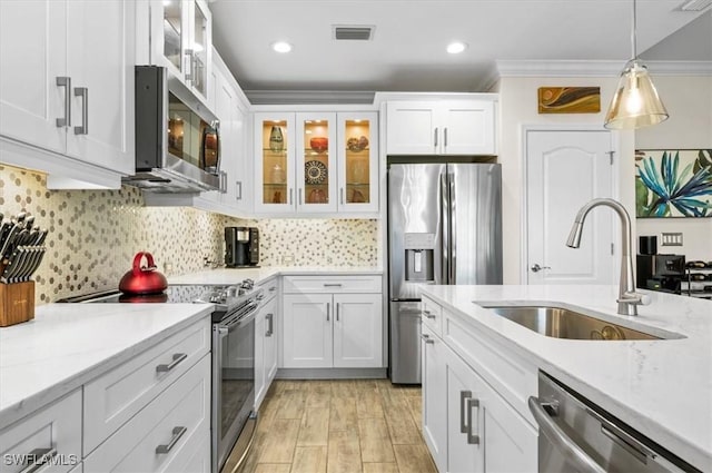 kitchen with stainless steel appliances, a sink, white cabinetry, visible vents, and crown molding