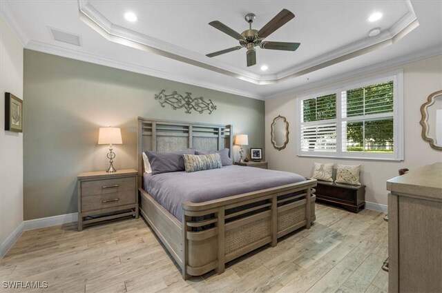 bedroom with ceiling fan, a raised ceiling, ornamental molding, and light hardwood / wood-style flooring