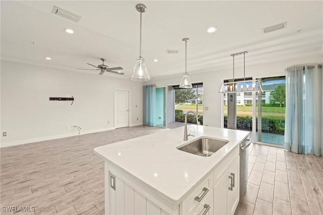 kitchen with white cabinetry, sink, ceiling fan, an island with sink, and decorative light fixtures