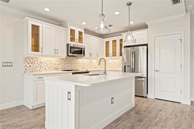 kitchen featuring appliances with stainless steel finishes, a kitchen island with sink, crown molding, sink, and pendant lighting