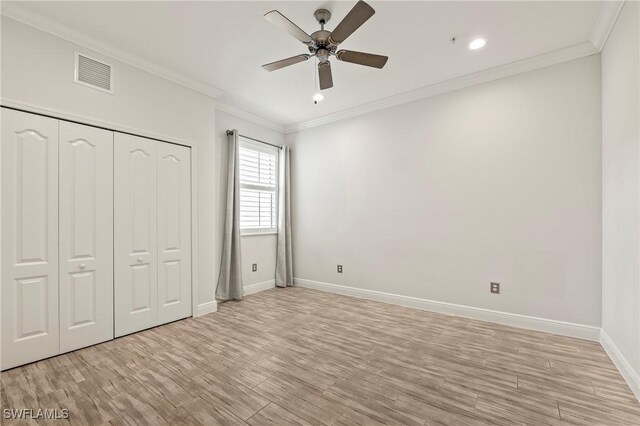 unfurnished bedroom with a closet, ceiling fan, crown molding, and light wood-type flooring