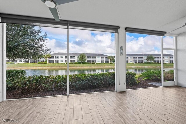 unfurnished sunroom featuring ceiling fan, plenty of natural light, and a water view