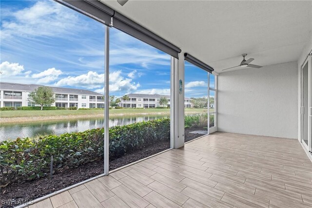 unfurnished sunroom featuring ceiling fan and a water view