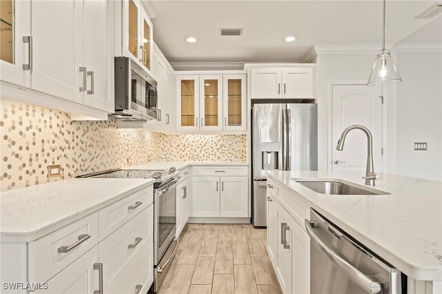 kitchen with sink, light stone counters, decorative light fixtures, white cabinets, and appliances with stainless steel finishes