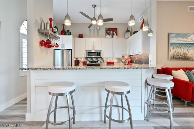 kitchen featuring white cabinetry, appliances with stainless steel finishes, and a breakfast bar