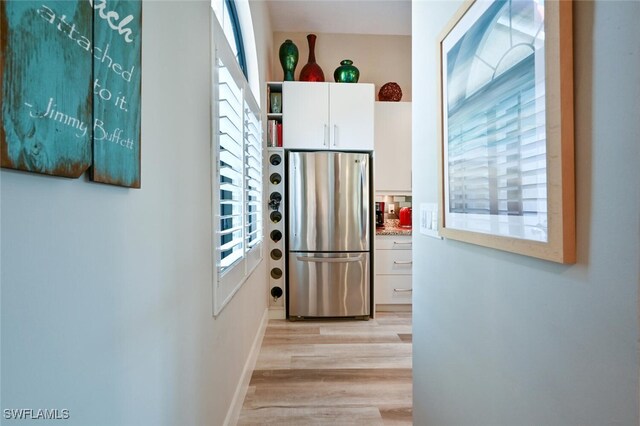 kitchen with light hardwood / wood-style floors, stainless steel refrigerator, and white cabinets