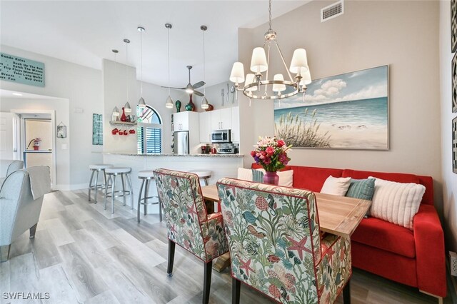 dining area featuring a towering ceiling, light wood-type flooring, and breakfast area