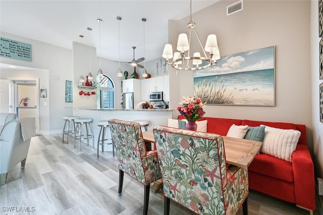 dining area with breakfast area, light hardwood / wood-style floors, and a high ceiling