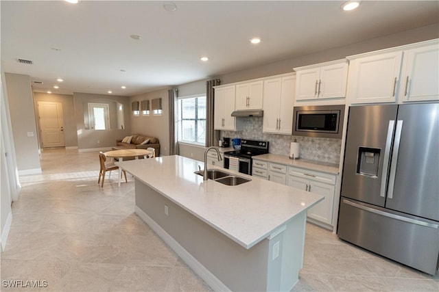 kitchen featuring tasteful backsplash, white cabinets, appliances with stainless steel finishes, under cabinet range hood, and a sink