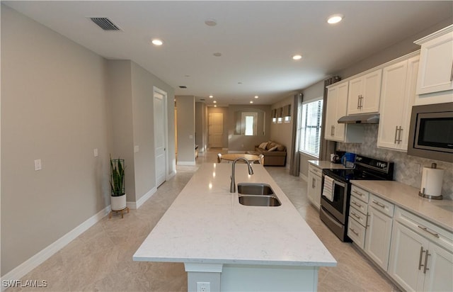 kitchen featuring under cabinet range hood, a sink, visible vents, appliances with stainless steel finishes, and backsplash