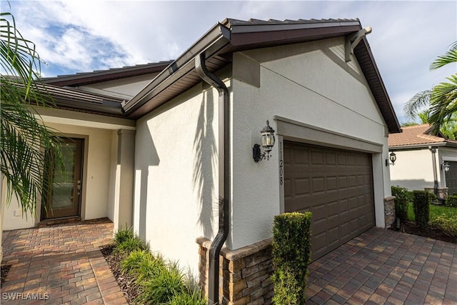 view of property exterior featuring a garage, decorative driveway, and stucco siding