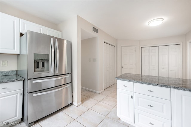 kitchen with dark stone counters, white cabinets, light tile patterned floors, and stainless steel fridge with ice dispenser