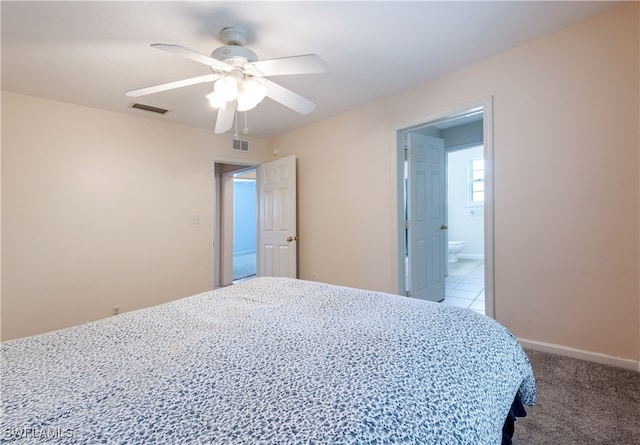 bedroom with ceiling fan, ensuite bathroom, and light carpet