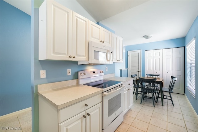 kitchen with light tile patterned floors, white appliances, and white cabinets