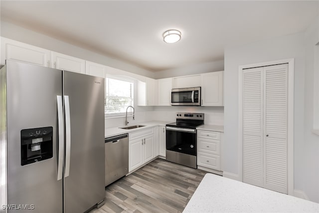 kitchen with white cabinets, light wood-type flooring, appliances with stainless steel finishes, and sink