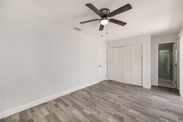 unfurnished bedroom featuring ceiling fan, a closet, and light wood-type flooring