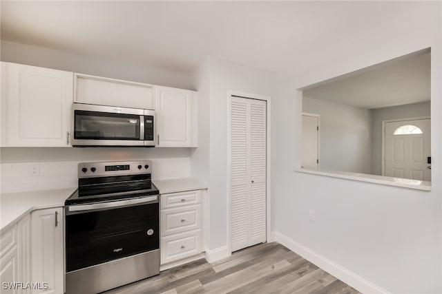 kitchen with white cabinetry, appliances with stainless steel finishes, backsplash, and light hardwood / wood-style flooring