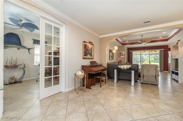 tiled living room with ornamental molding, a tray ceiling, and ceiling fan