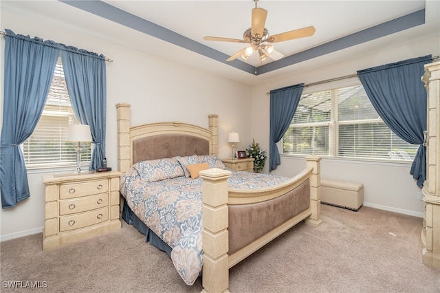 bedroom featuring ceiling fan, light carpet, and a tray ceiling